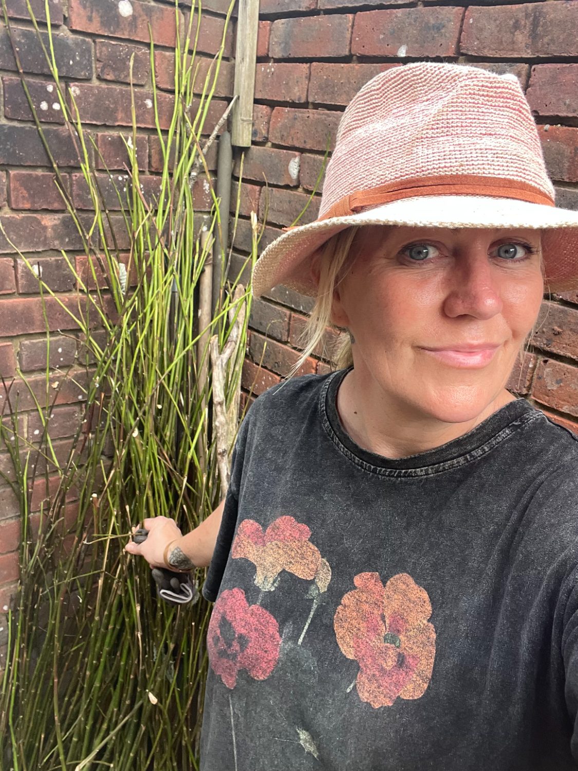 Josephine in the garden in a sun hat beside tall green stems